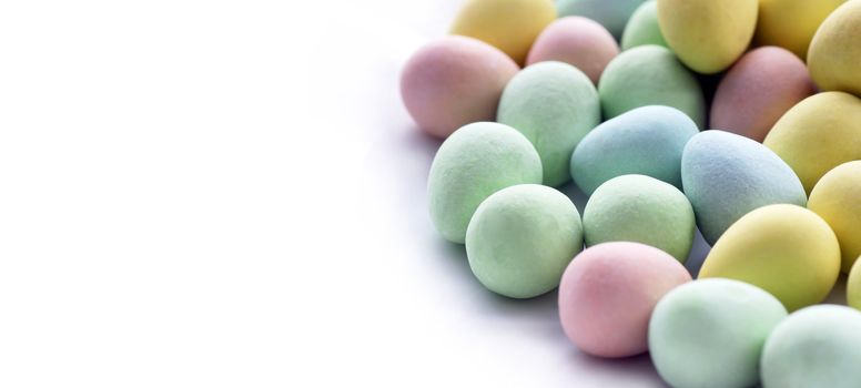 Panorama of small Easter egg treats: hard candy pastel color covered chocolates. 