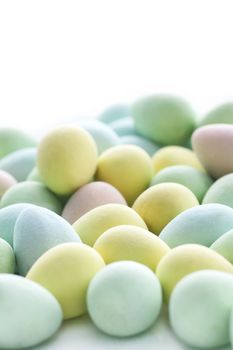 High key vertical of small pastel colored Easter egg candy fading in the far white background.