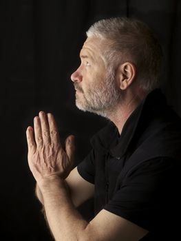 senior man praying on black background