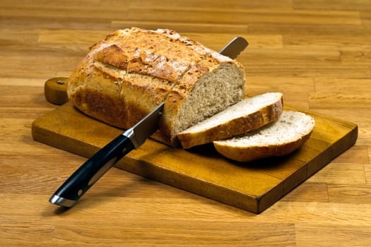 Wooden cutting board with sliced white bread and knife on wooden table