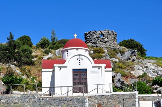 Travel photography: Greek chapel with the ruins of an old windmill in the 

background. Crete, Greece.
