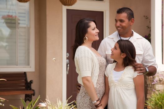 Small Hispanic Mother, Father and Daughter in Front of Their Home.