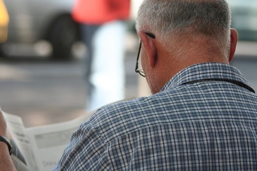 Senior man reading a newspaper outdoors