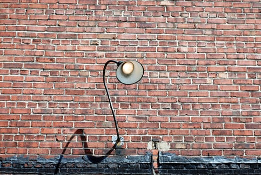 Grunge brick wall with curved lamp fixture turned on