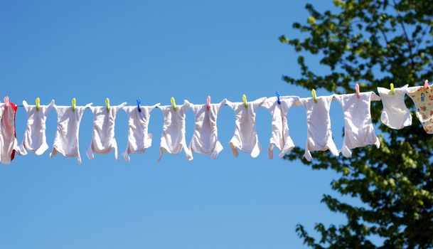 Clothes line full of reusable baby diapers in front of a clear blue sky