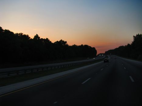 Florida Highway Sunset is set against a blue white and orange sky in this beautiful composition with the road and lines leading straight towards the viewer.
