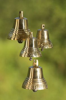 Four brass handbells on a green background