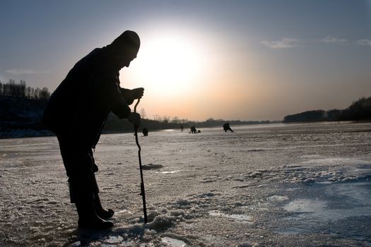 The fisherman on winter fishing drills ice