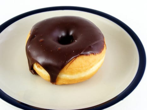 A chocolate iced donut on a plate against a white background.