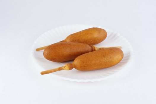 Three corn dogs on a paper plate