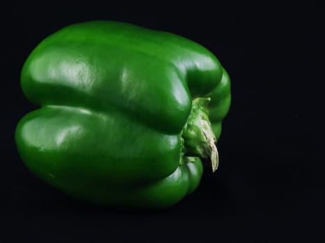 A green bell pepper against a black background.