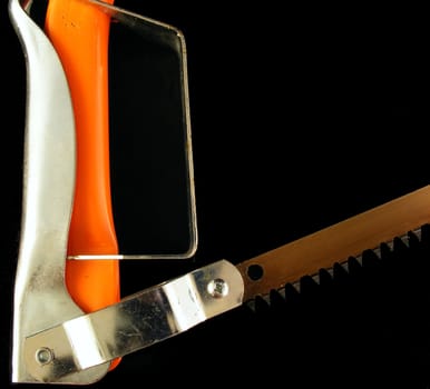 An orange hacksaw handle and blade against a black background.