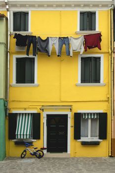 A house in Murano, one of the Venetian islands, with washing hanging on a line, a broom by the door and a child's bicycle.