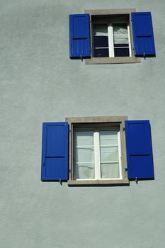 Bright blue shutters on a grey wall. Space for text at the base of the image.