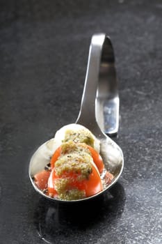 Amuse bouche with a cherry tomato, mozzarella and pesto