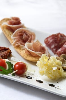 Plate of antipasti with parmaham on toast, cheese and cherry tomatoes