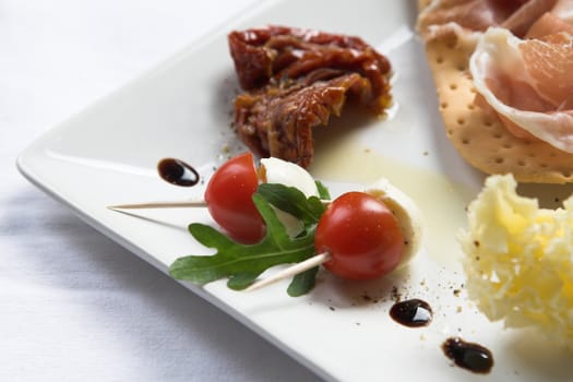 Plate filled with various antipasti (focus is on the small cherry tomatoes in the front)