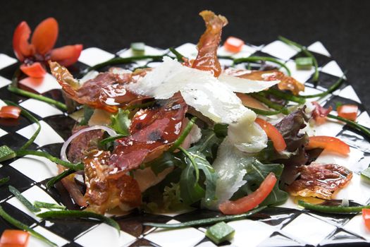 Delicious healthy salad made up with crispy parmaham, tomatoes, parmesan cheese and a flower tomato