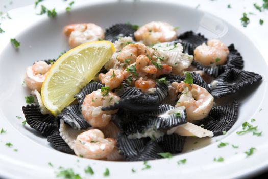 Black pasta with big tigerprawns and a lemon