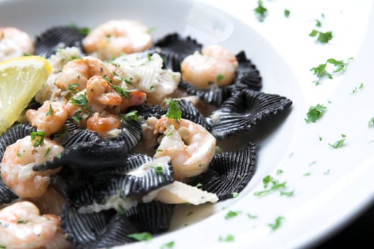 Pasta dish with black pasta and tigerprawns