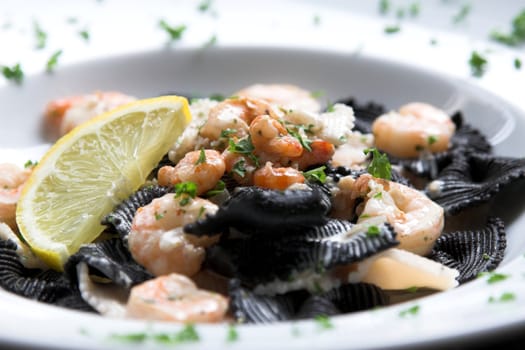 Pasta dish with seafood, big tigerprawns and a lemon for adding some juice