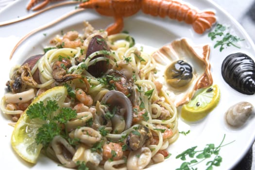 Delicious seafood dish with spaghetti, mussels, squid and shrimps with a slice of lemon