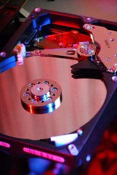 Open hard disk close-up with electronics in the background