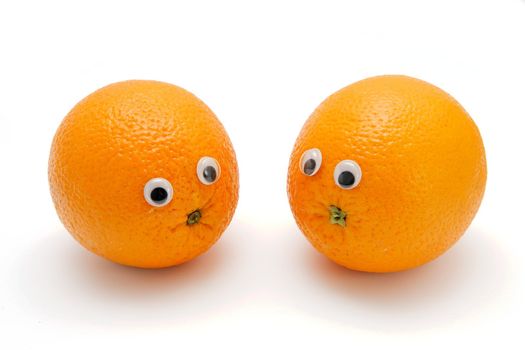 Two funny orange fruits with eyes on white background