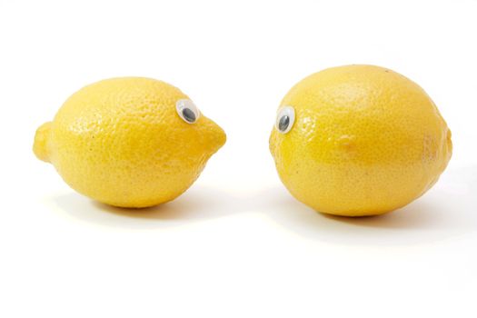 Two funny lemon fruits with eyes on white background