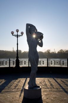 Sculpture of a girl with a pitcher in the backlight