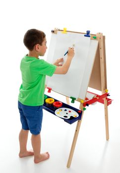 A little boy starting to paint a picture using acrylic paints and art paper on an easel.  White background.