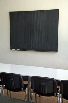 empty blackboard, black chairs, white table
