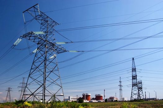 Electrical power lines and nuclear power station under clear blue sky