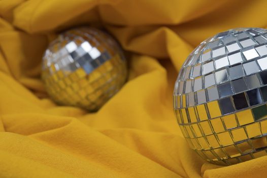 two disco balls on yellow background, shallow depth of view