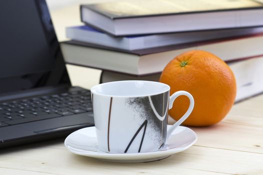 cup of coffee, books, laptop and orange