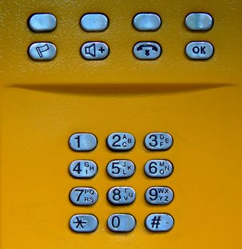 Public phone yellow keypad closeup