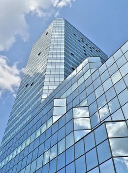 Glass building in Warsaw under blue sky with clouds