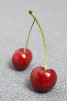 two cherries on grey background, shallow depth of view