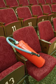 red fire extinguisher on purple wooden theatre seats