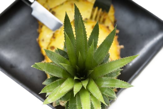 ripe vibrant pineapple sliced on a black plate with knife and fork