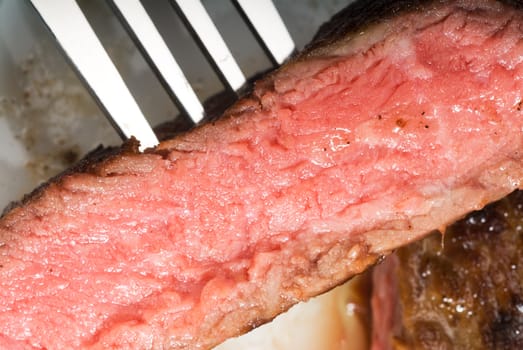 fresh juicy beef ribeye steak sliced ,with fork ove a plate