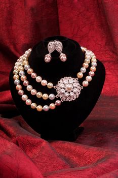 Pearl necklace and earring on a red background