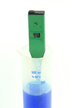 Picture of process of measuring of temperature of blue coloured solution with green waterproof electronic, digital, temperature tester. 
