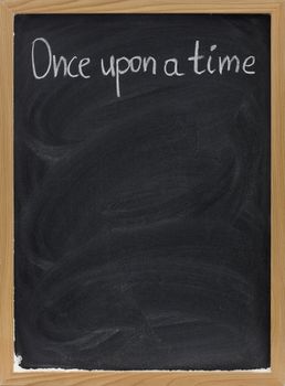 Once upon a time - stock phrase for opening oral narratives and fairytales handwritten with white chalk on blackboard, copy space below