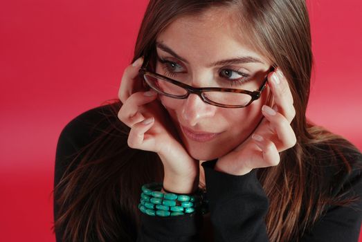 beautiful girl showing off her glasses on a red background