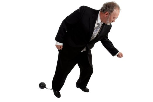 Businessman tring to move with a ball and chain attached to his leg 