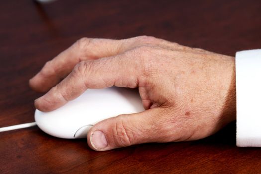 Elderly hand using a computer mouse on a desk