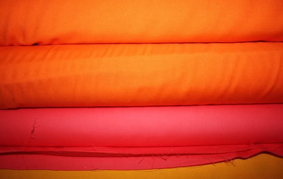 A background of fabric rolls in bright colors.