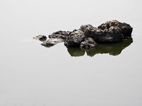 Detail of a small rock lying above water surface seemingly floating in space