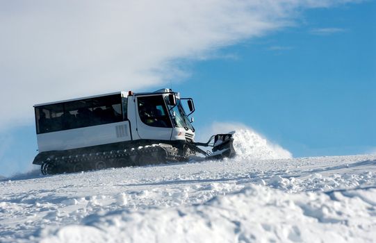 Ski slope with a white ratrak doing track maintenance